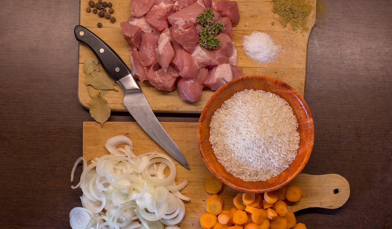 砧板上放了肉、洋蔥、紅蘿蔔及米