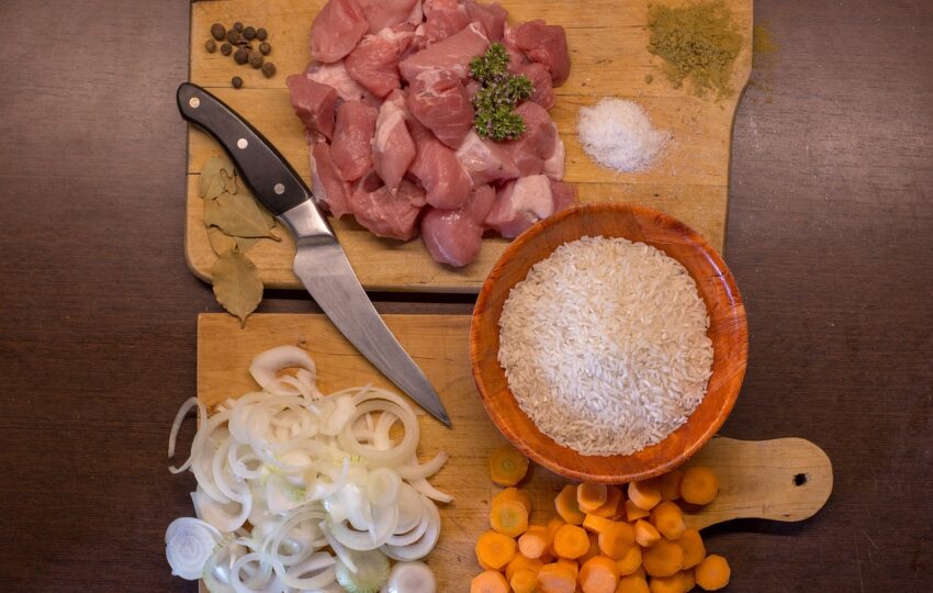 砧板上放了肉、洋蔥、紅蘿蔔及米