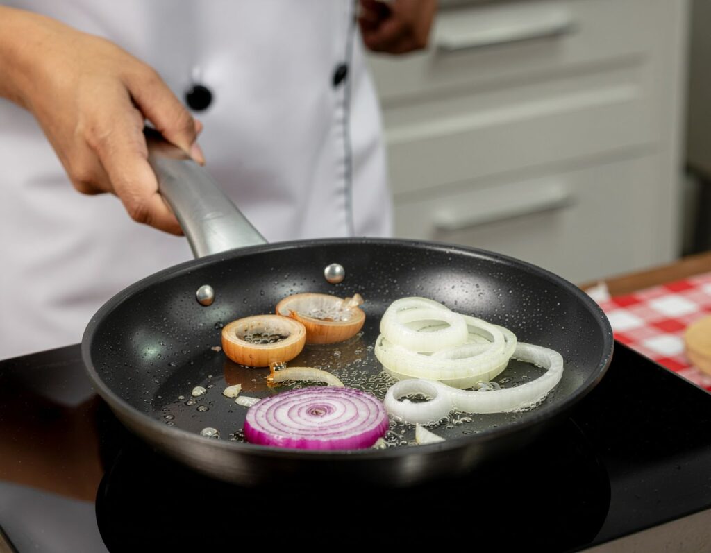 廚師在平底鍋中炒洋蔥片，白洋蔥香氣撲鼻、黃洋蔥轉為金黃、紫洋蔥色澤誘人，畫面呈現不同品種洋蔥的烹調變化。