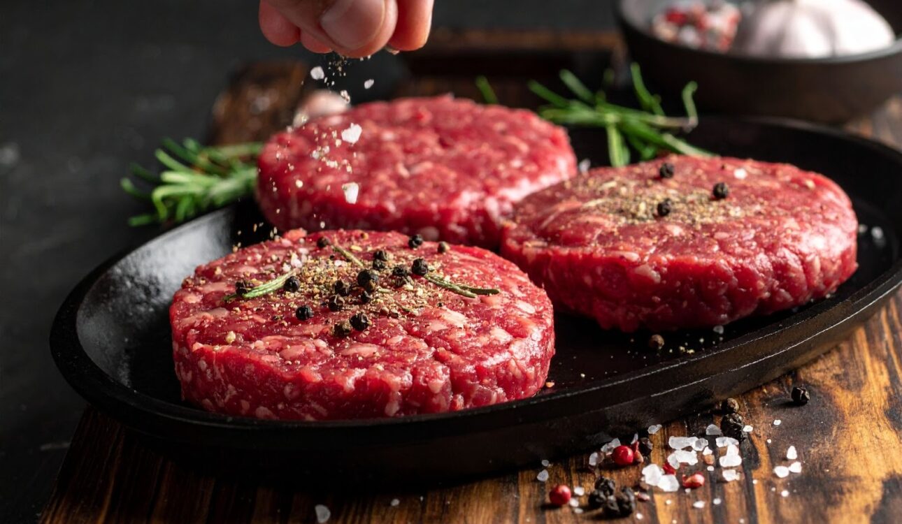 鐵板上漢堡肉煎得油花四濺，撒上現磨黑胡椒與鹽粒