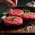 鐵板上漢堡肉煎得油花四濺，撒上現磨黑胡椒與鹽粒