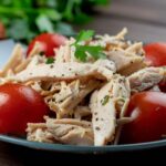 透明玻璃盤中盛著黑胡椒醬涼拌雞絲與蔬菜的成品，醬汁光澤誘人，配色鮮豔，強調清爽又富香氣的夏日開胃料理。