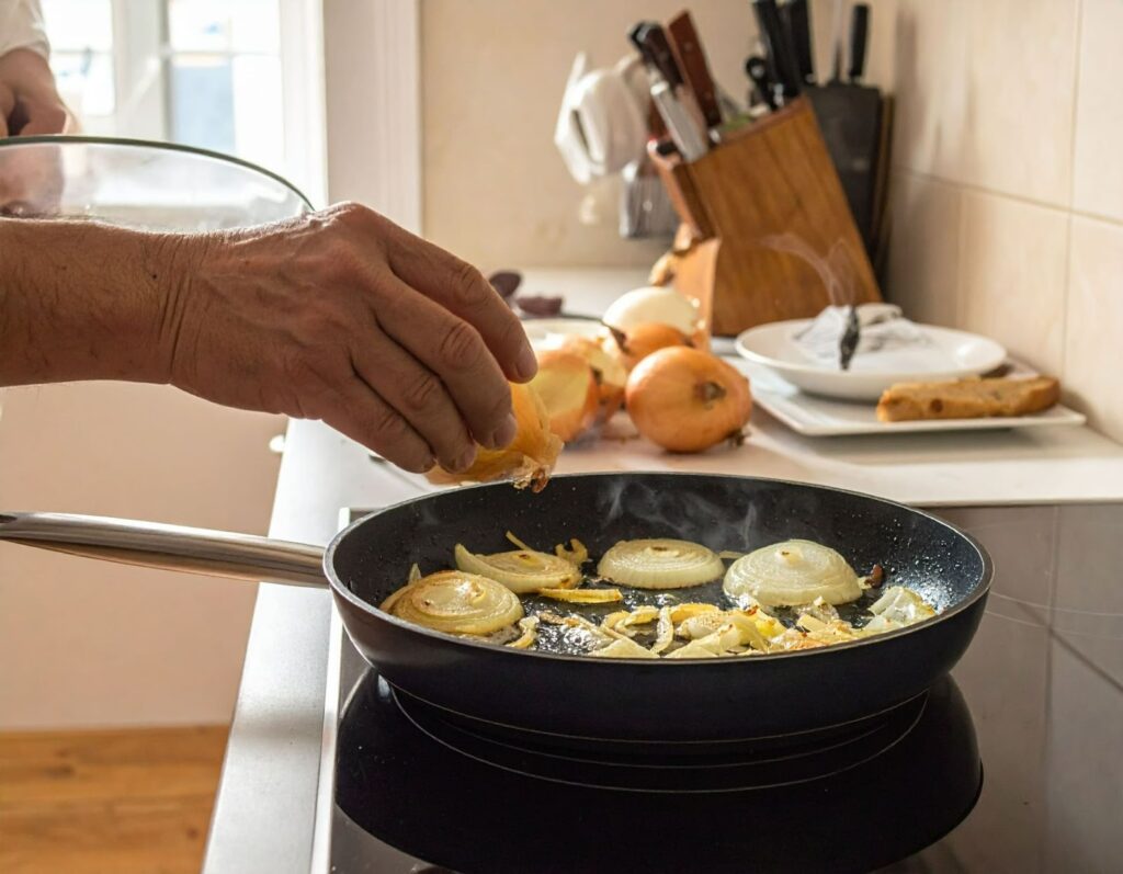 廚房中平底鍋慢慢炒洋蔥至金黃色